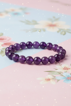 Purple beaded bracelet on a floral background