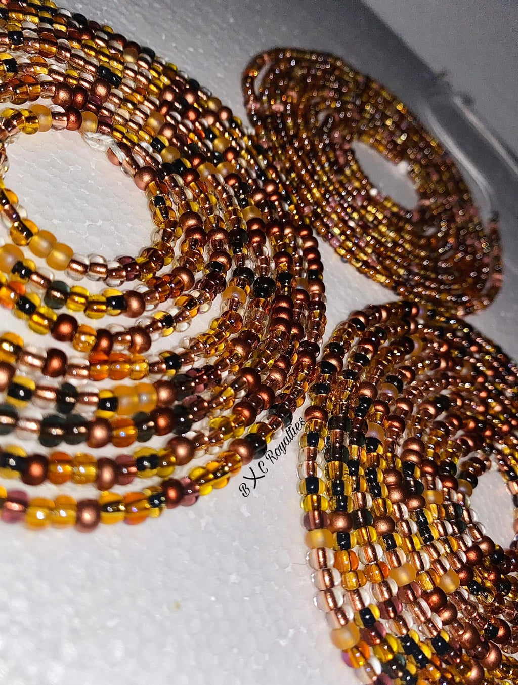 Multiple beaded bracelets in brown, black, and gold on a white surface