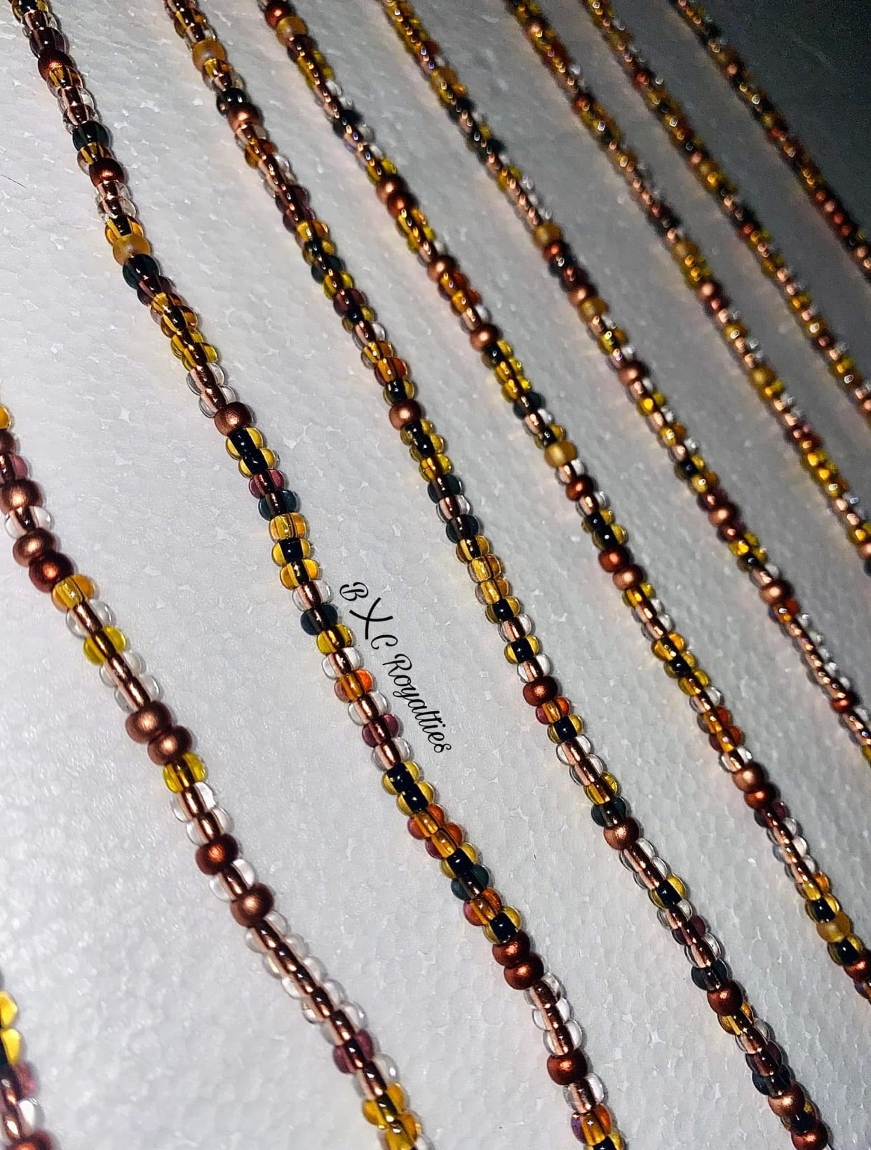 Beaded chains in brown, black, and gold on a white background