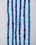Multiple strands of blue beaded necklaces on a textured white background
