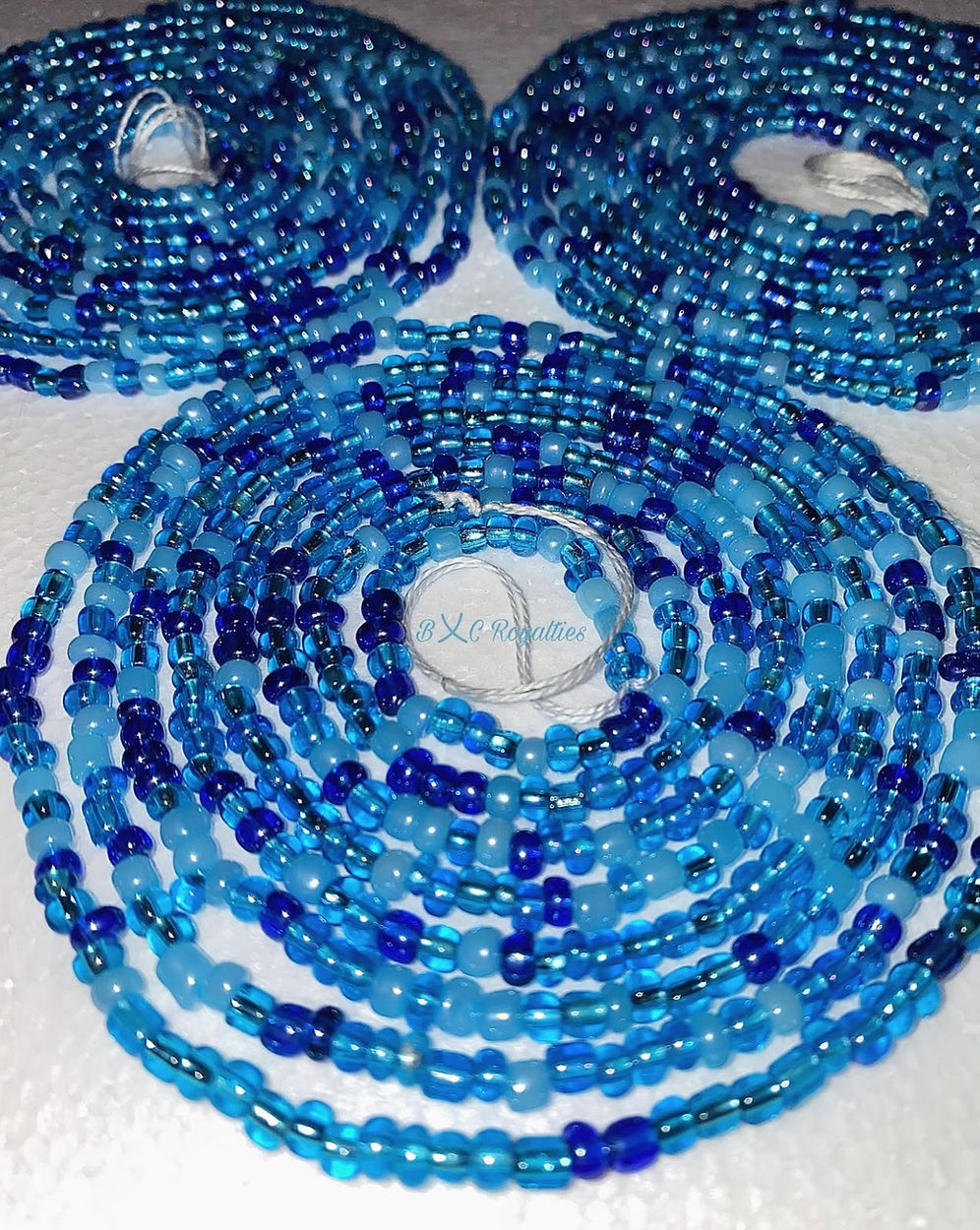 Two spools of blue and black beaded strands on a white background