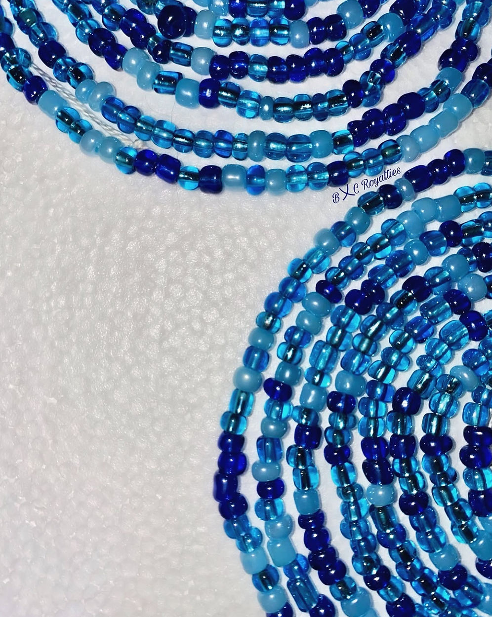 Multiple strands of blue beads on a white background