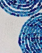 Multiple strands of blue beads on a white background