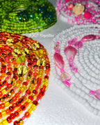 Colorful beaded necklaces on a textured surface with 'BXC Royalties' branding.