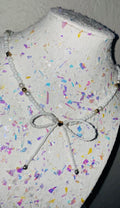 Mannequin head with colorful confetti pattern and decorative bow on a plain background