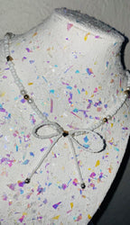 Mannequin head with colorful confetti pattern and decorative bow on a plain background