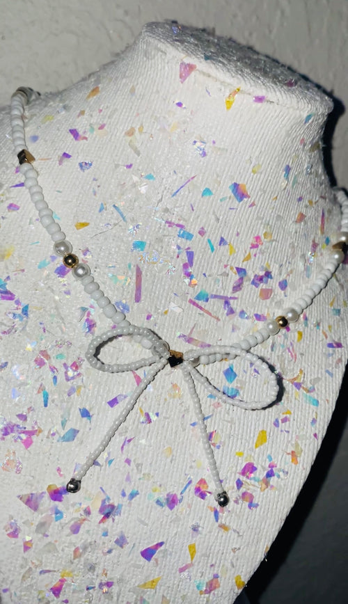 Mannequin head with colorful confetti pattern and decorative bow on a plain background