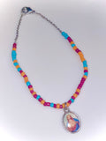 Colorful beaded necklace with a Virgin Mary pendant on a white background