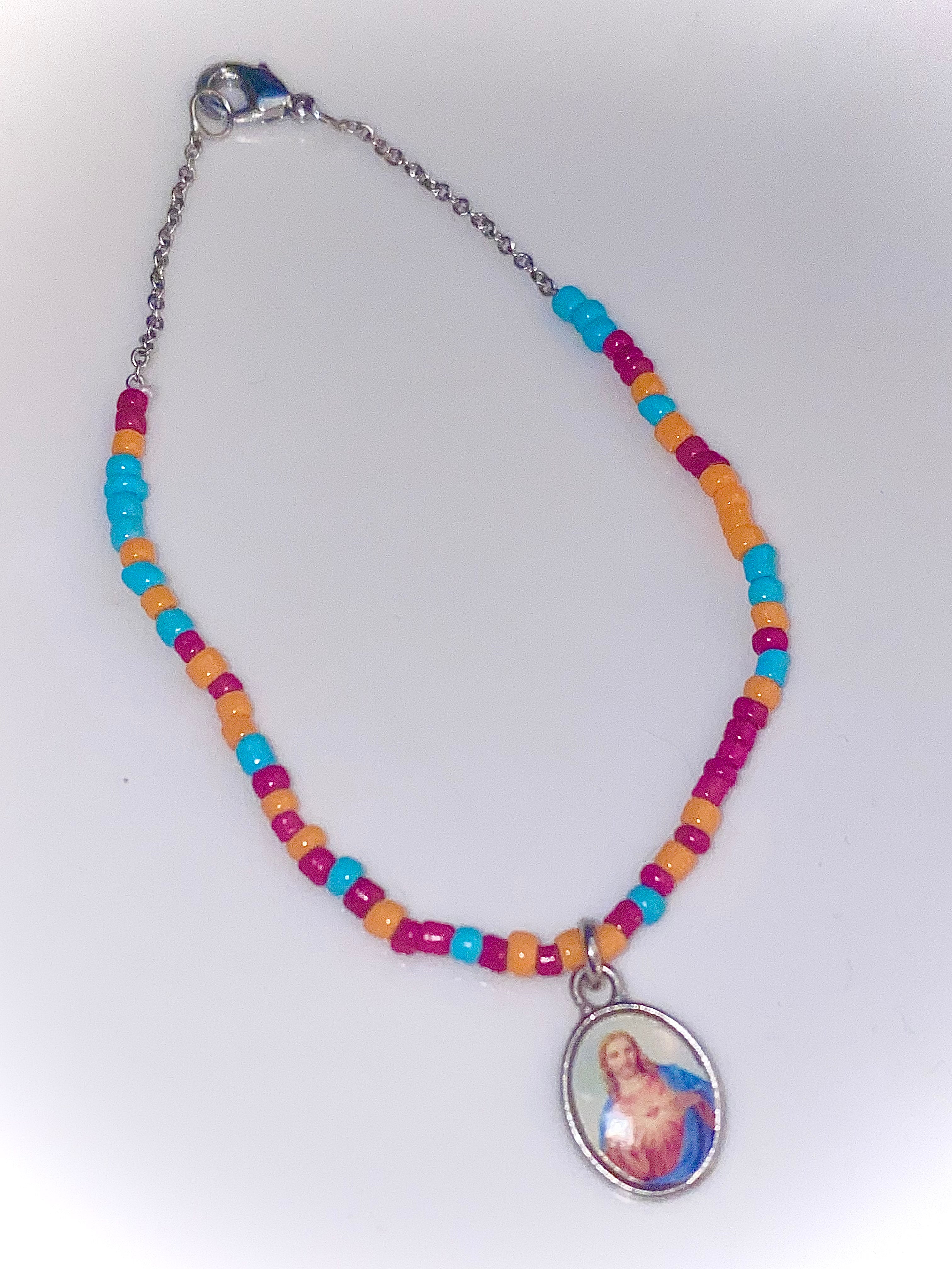 Colorful beaded necklace with a Virgin Mary pendant on a white background
