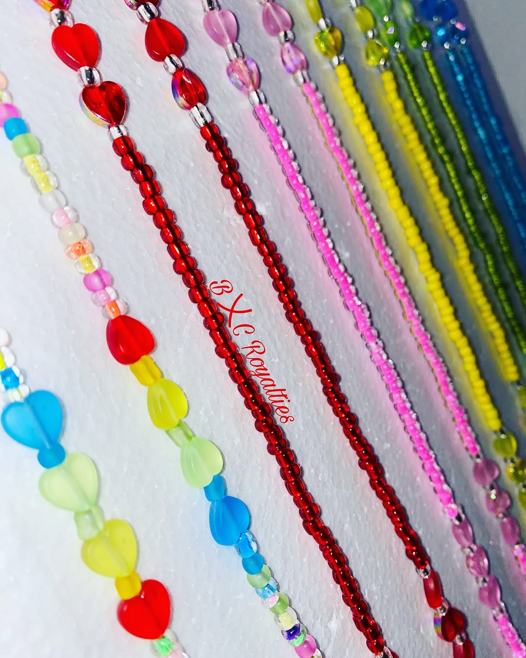 Colorful beaded necklaces on a white background with 'BXC Royalties' branding.
