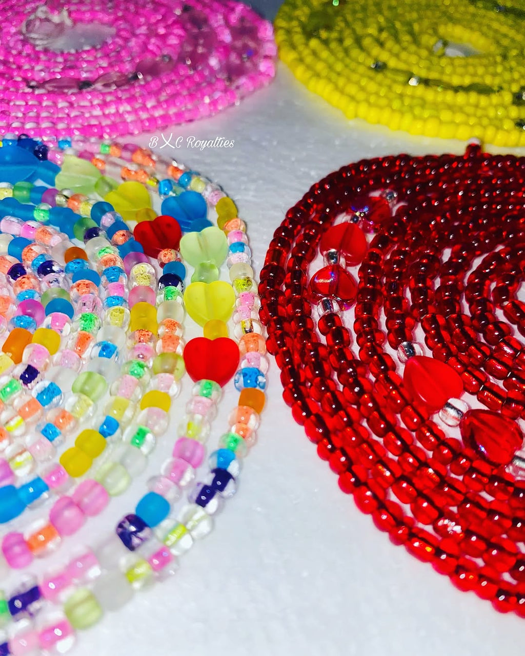 Colorful beaded necklaces with heart shapes on a white surface