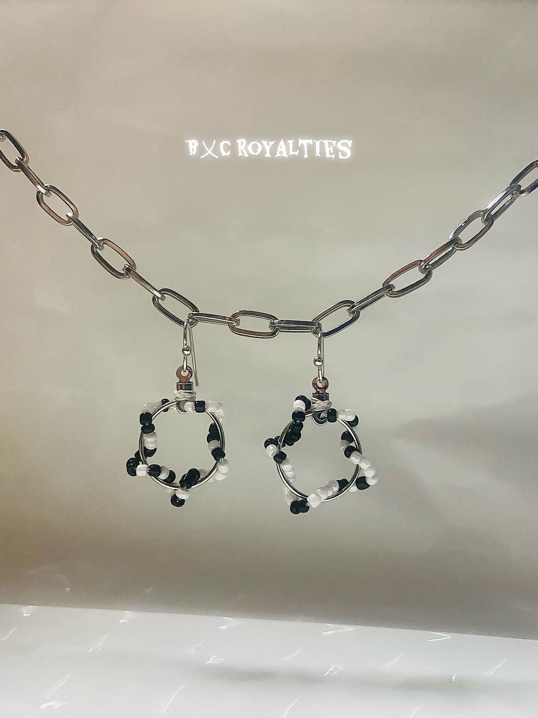 Earring set with black, white, and silver design on a neutral background