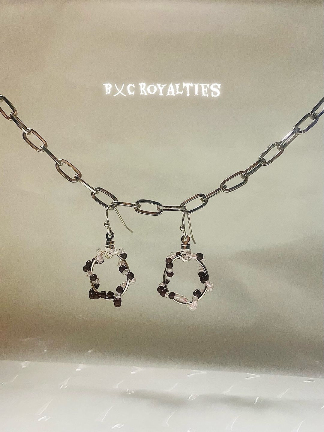 Earrings set on a beige background with 'BXC Royalties' branding.