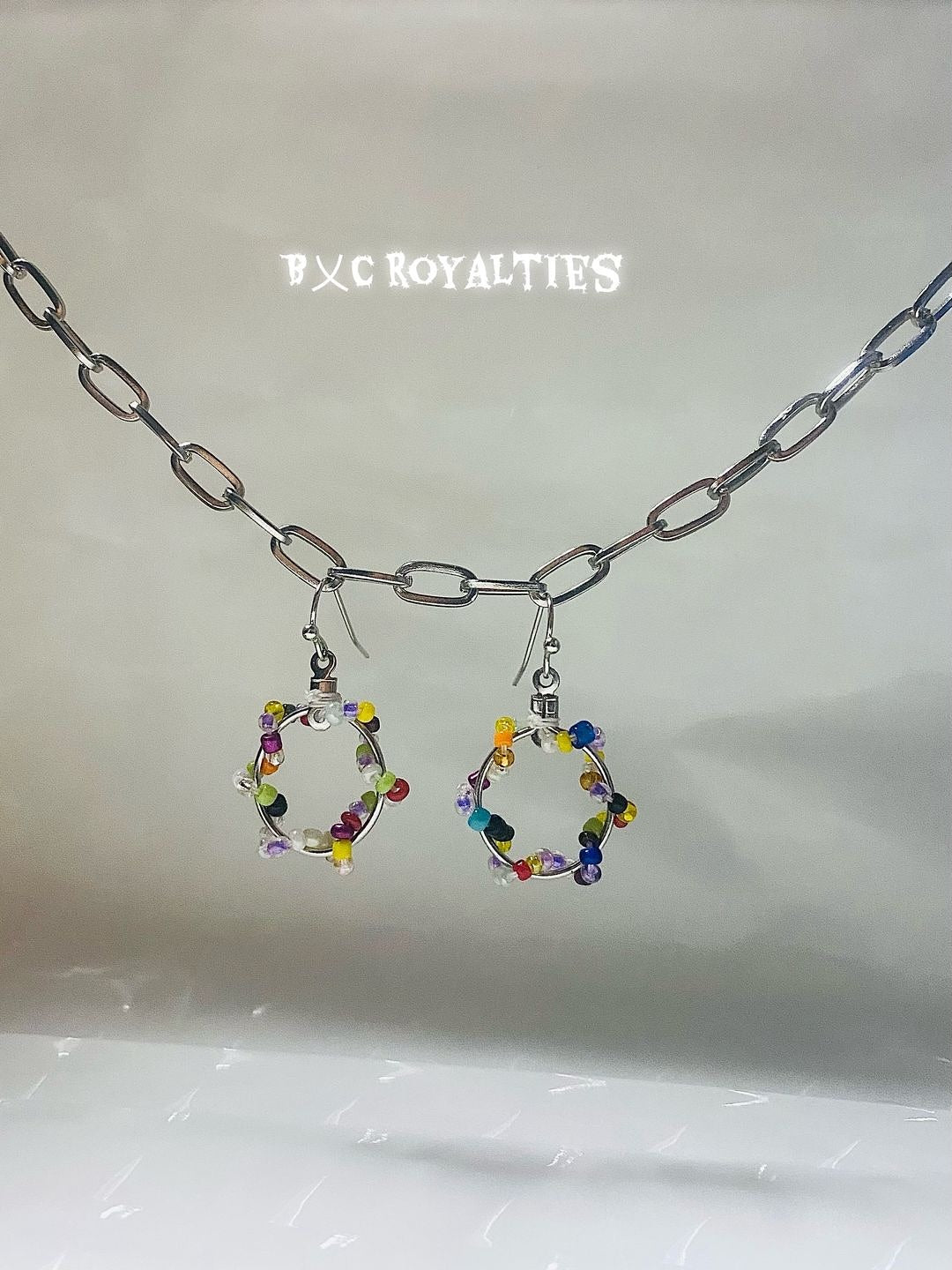 Colorful hoop earrings on a chain with 'BXC Royalties' branding.