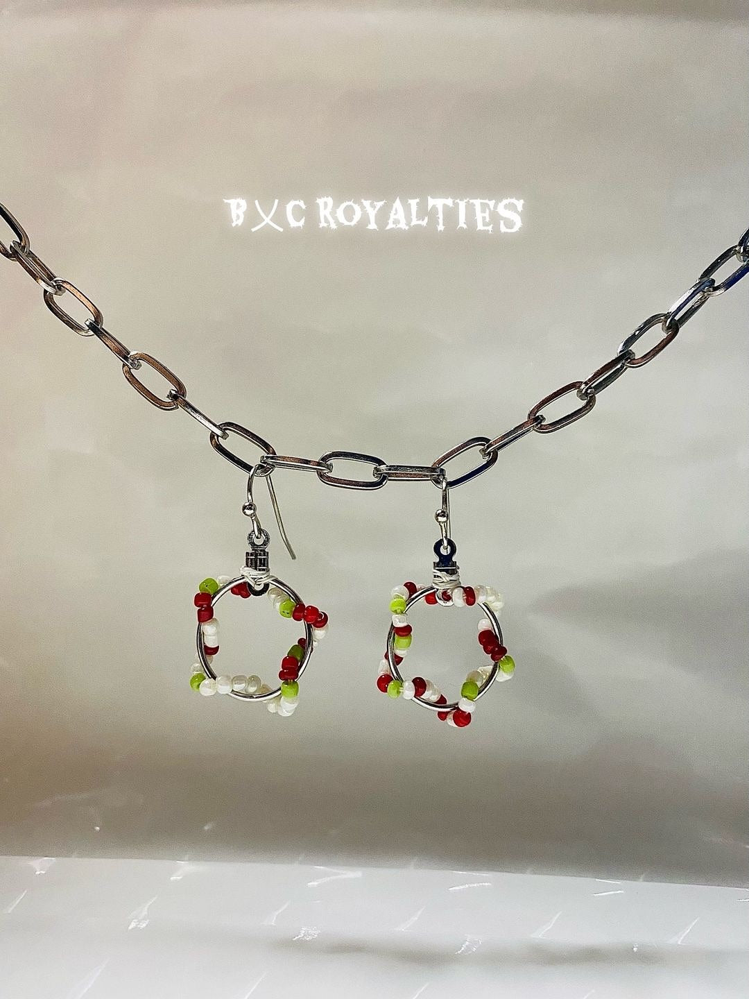 Earrings with circular design and colorful beads on a chain, branded 'BXC Royalties'.