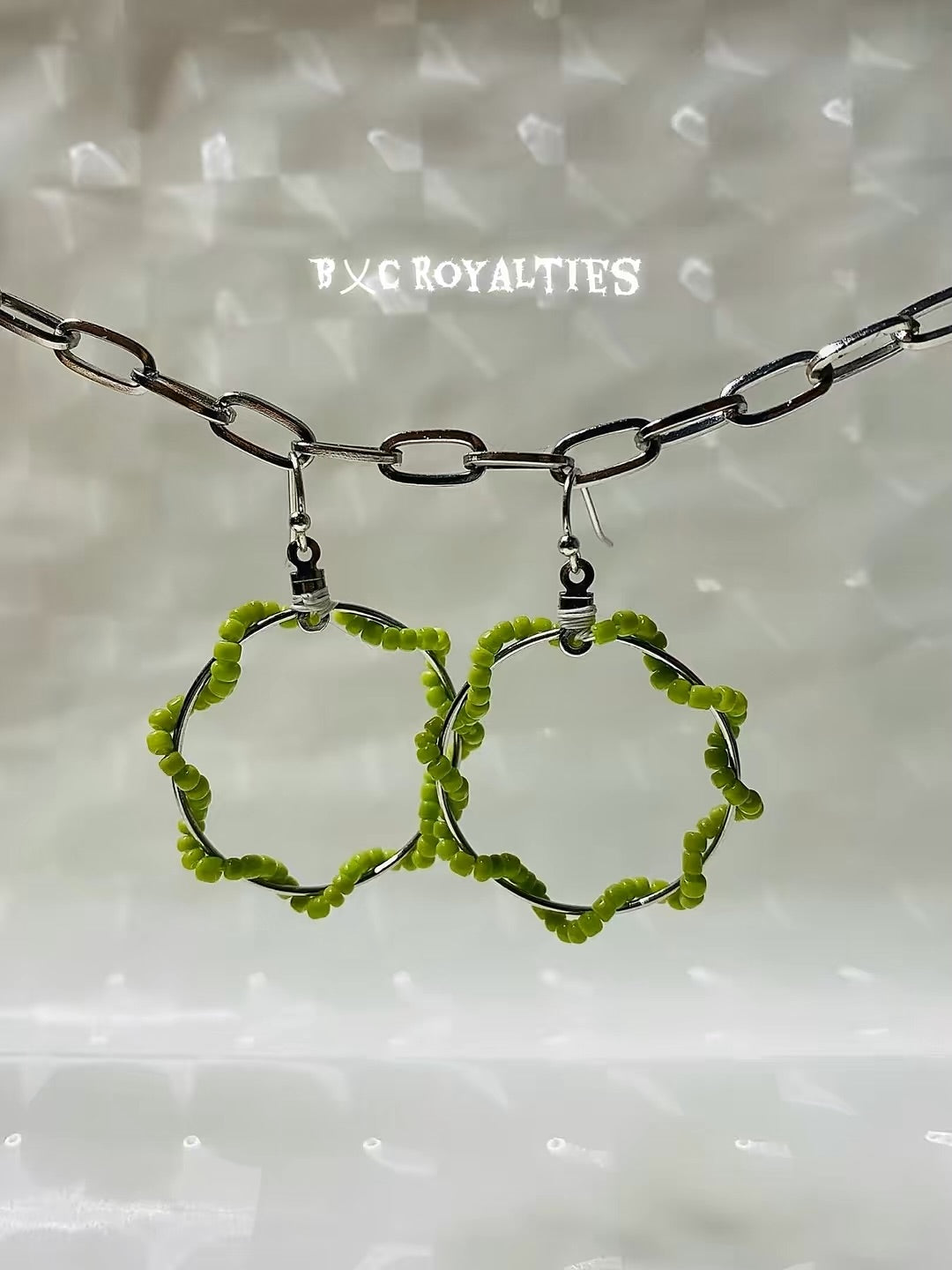 Lime Green hoop earrings on a chain against a textured white background with 'BXC Royalties' branding.