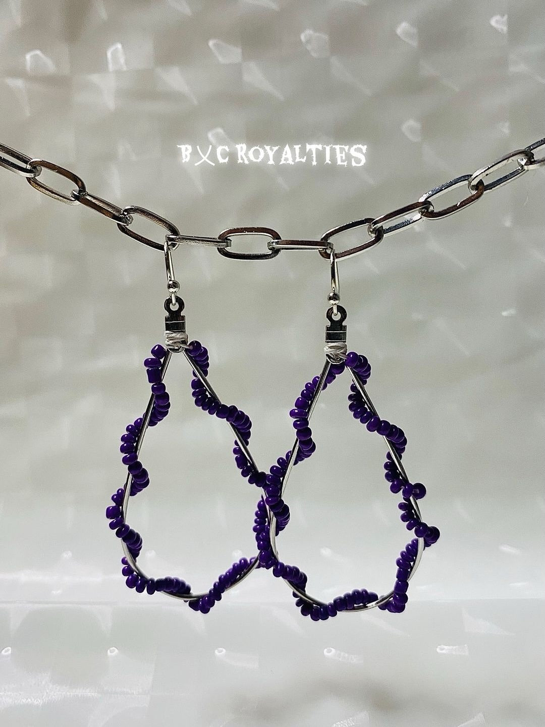 Purple beaded earrings on a chain against a light background