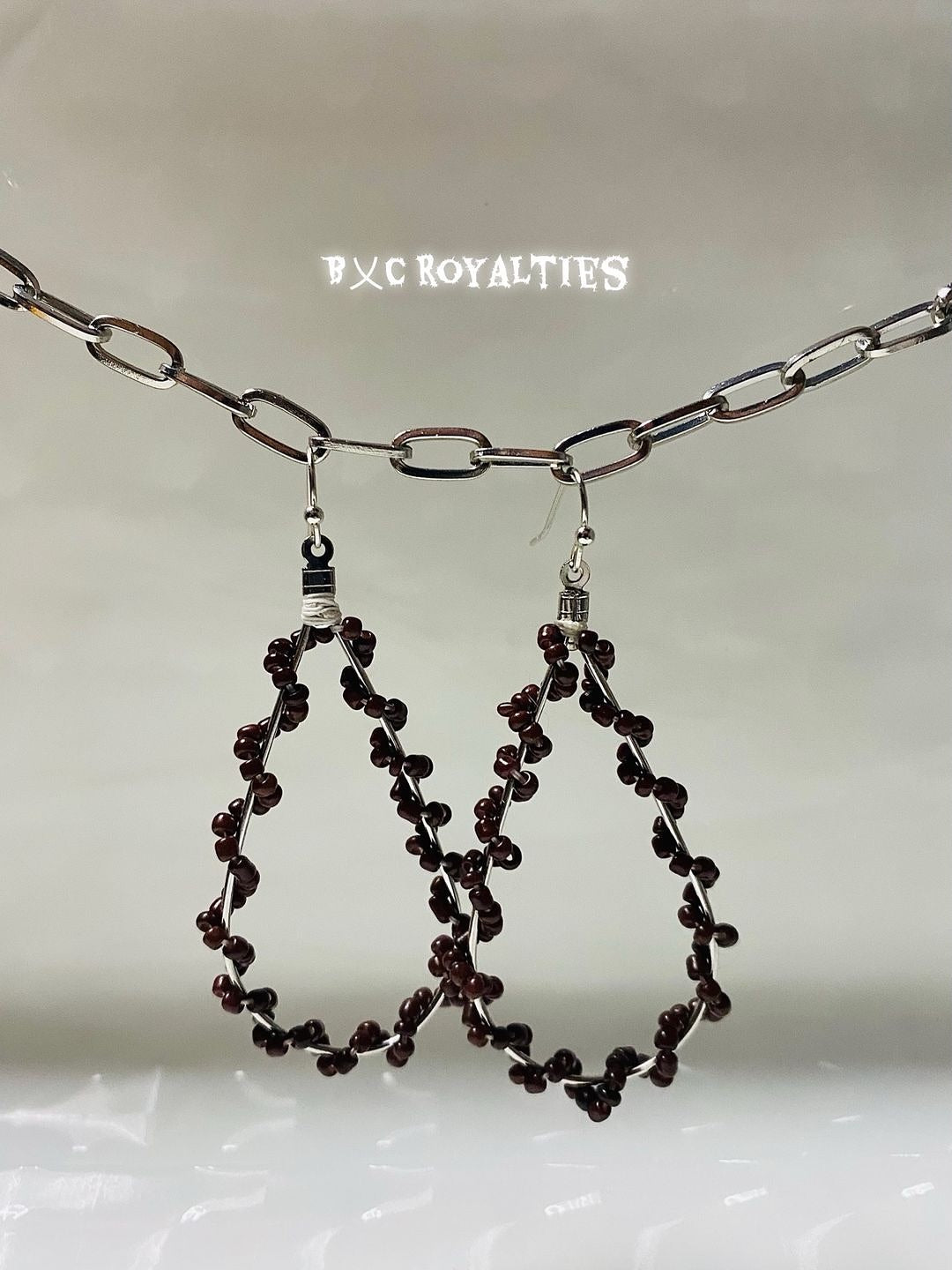 Pair of beaded hoop earrings with a chain on a light background