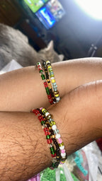 Close-up of a wrist wearing multiple non-stretch beaded bracelets with a blurred background