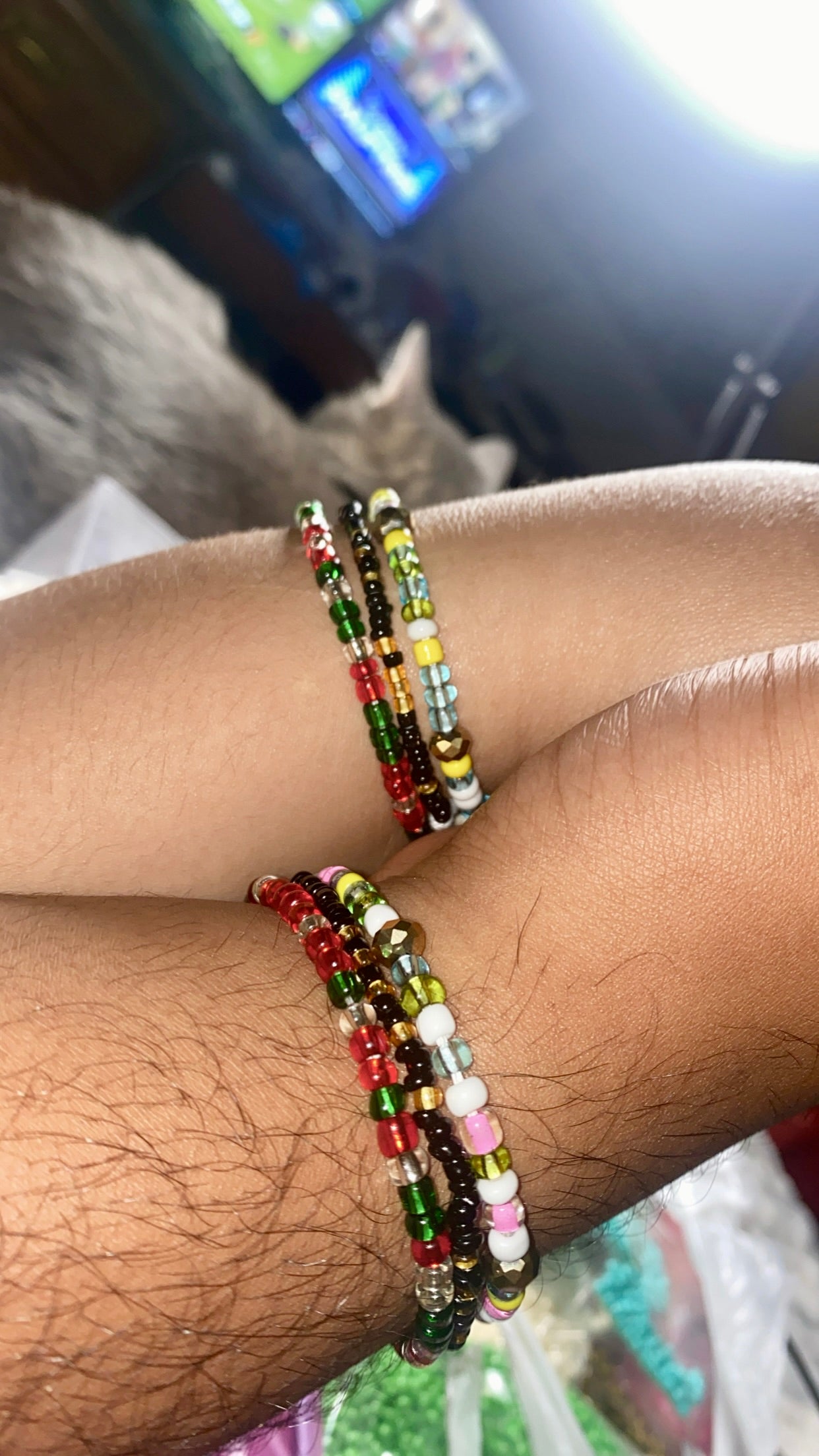 Close-up of a wrist wearing multiple non-stretch beaded bracelets with a blurred background