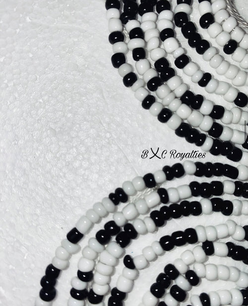Close-up of black and white beaded strands on a textured white background with 'BXC Royalties' branding.