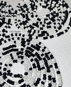 Close-up of black and white beaded strands on a textured surface