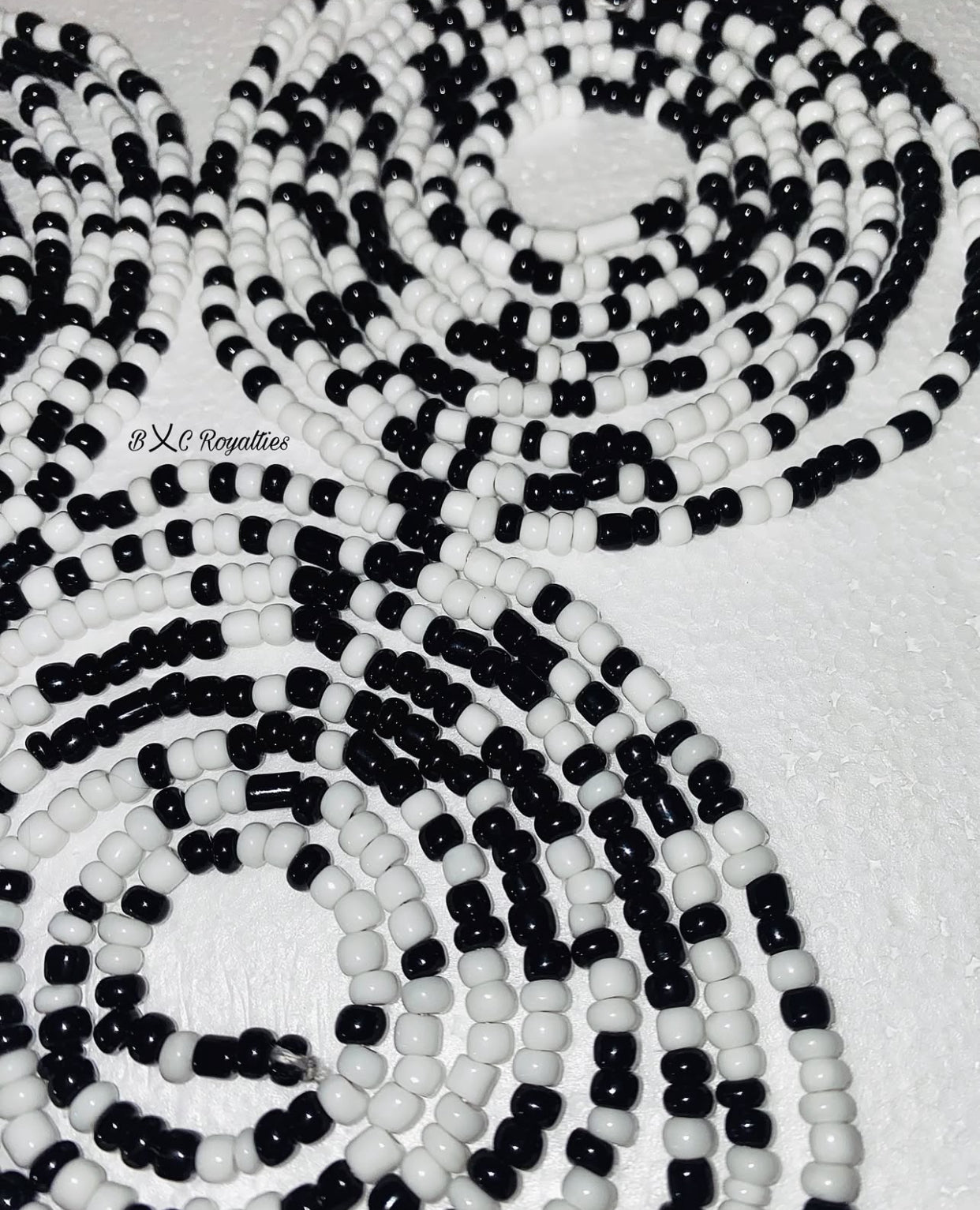 Close-up of black and white beaded strands on a textured surface