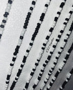 Close-up of black and white beaded strands on a textured white background