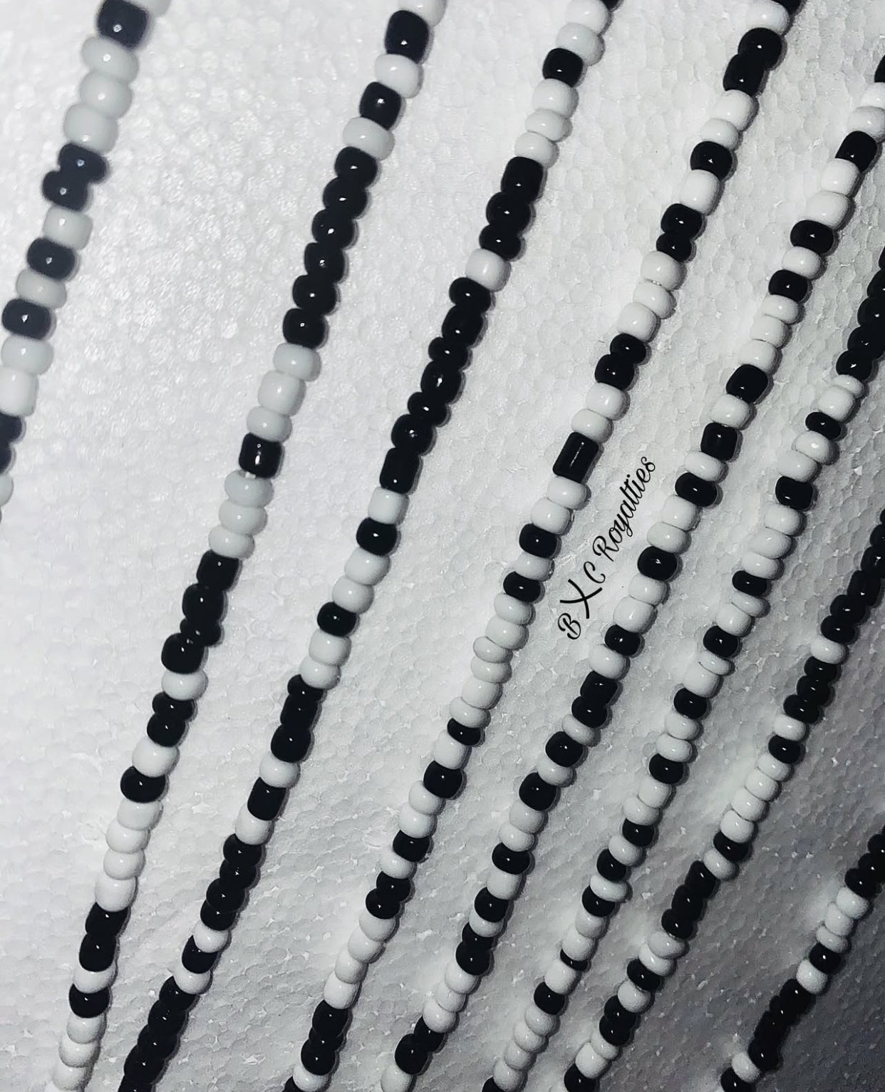 Close-up of black and white beaded strands on a textured white background