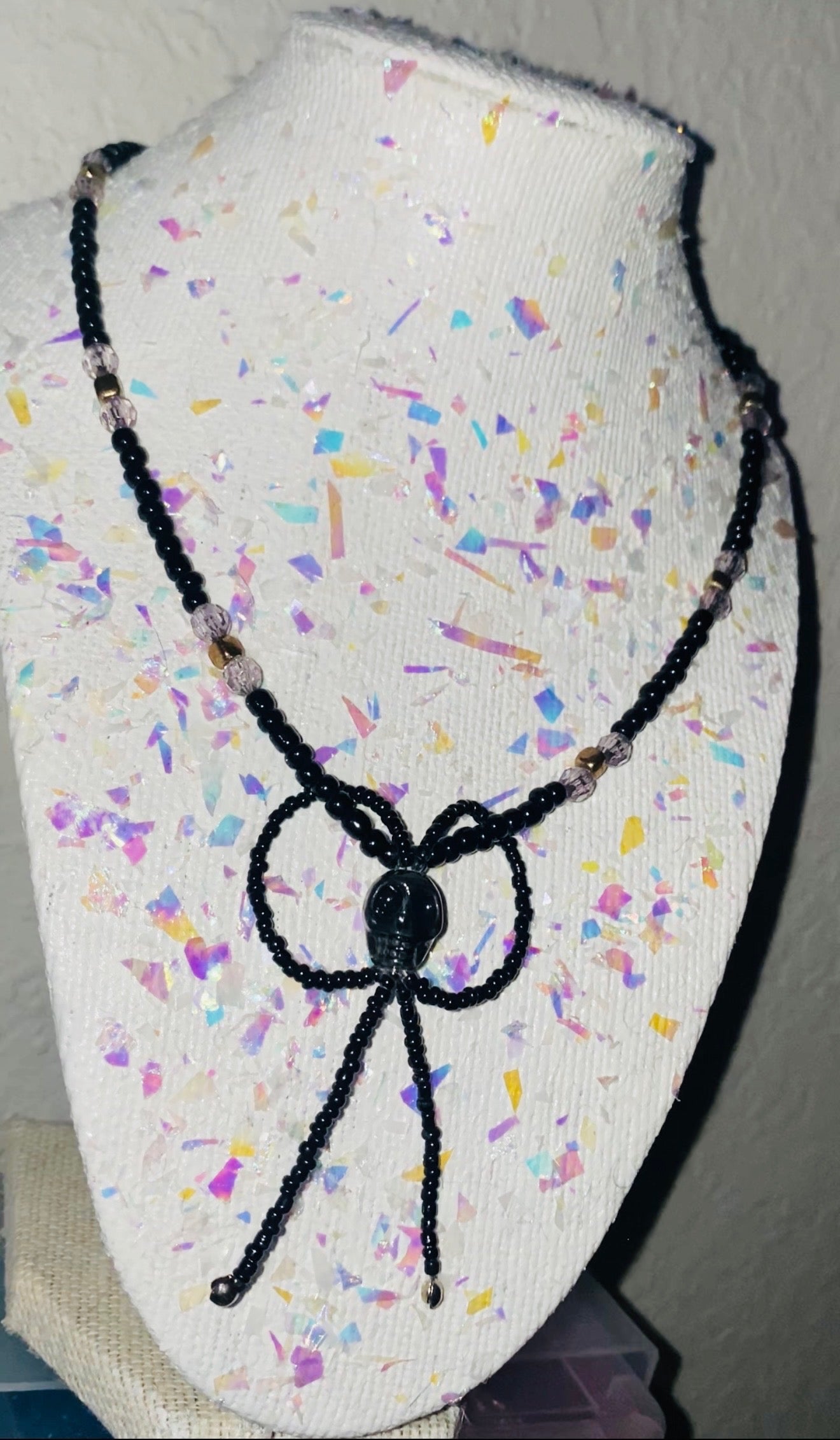 Black beaded necklace on a colorful textured stand
