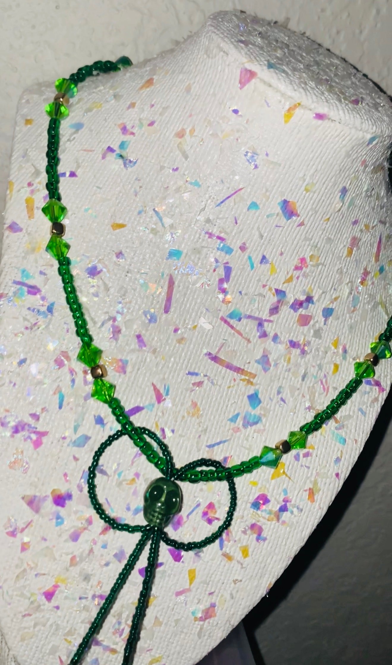 Green beaded necklace on a mannequin with a colorful background