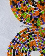 Colorful beaded necklace with orange, green, black, and purple beads on a textured white background.