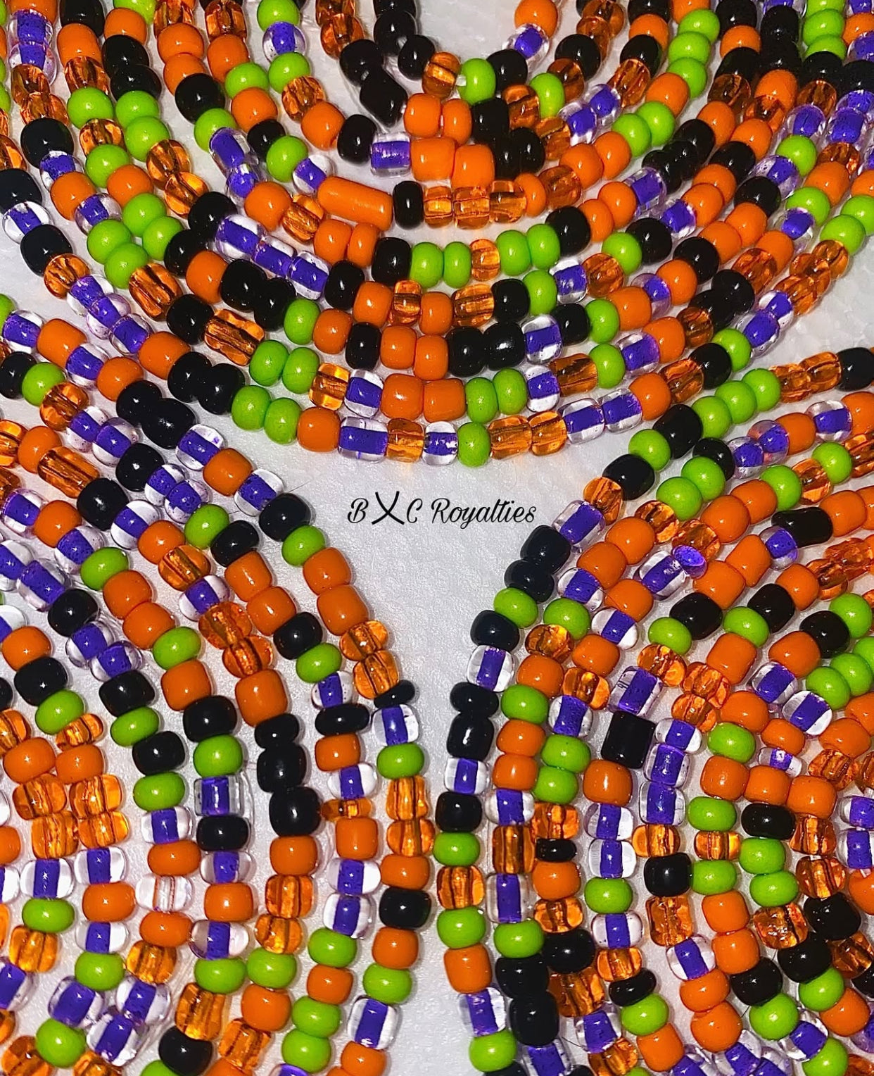 Colorful beaded necklace with orange, green, black, and purple beads on a white background.