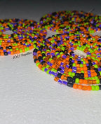 Colorful beaded necklace with orange, green, and black beads on a gray background.