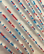 Close-up of a beaded pattern with red, blue, and white beads on a textured surface.