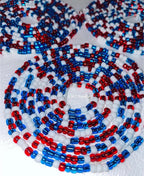 Close-up of a beaded necklace with red, white, and blue pattern on a white background