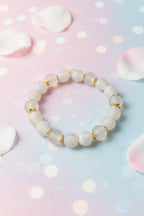 Bracelet with light-colored beads on a marble surface, add gold flower
