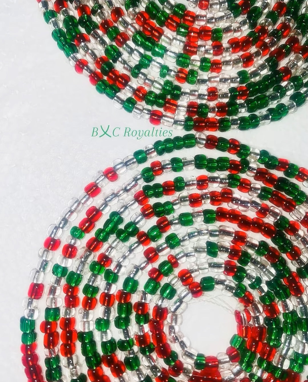 Close-up of red, green, and clear beaded strands on a white background with 'BXC Royalties' branding.