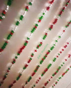 Decorative string with red, green, and clear beads on a white background