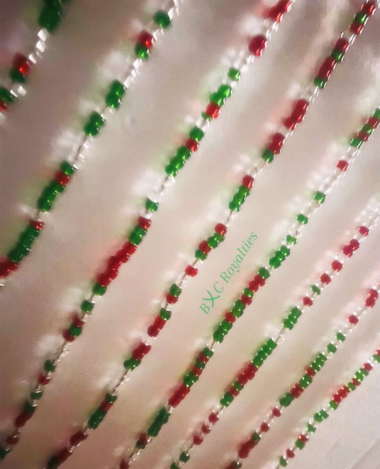 Decorative string with red, green, and clear beads on a white background