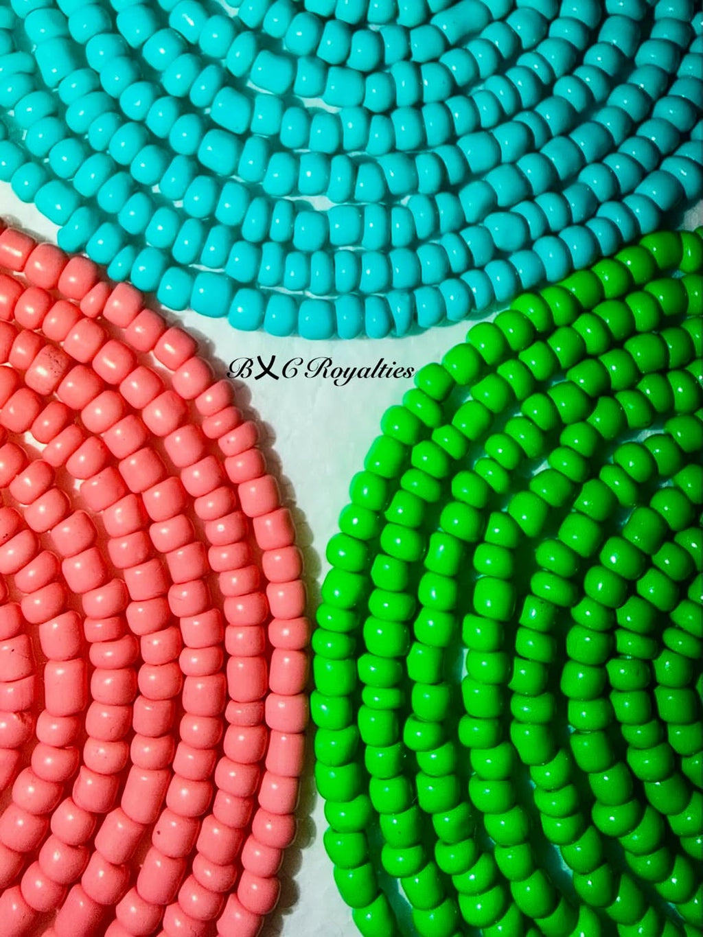 Close-up of colorful beads in turquoise, pink, and green on a white background with 'BXC Royalties' branding.