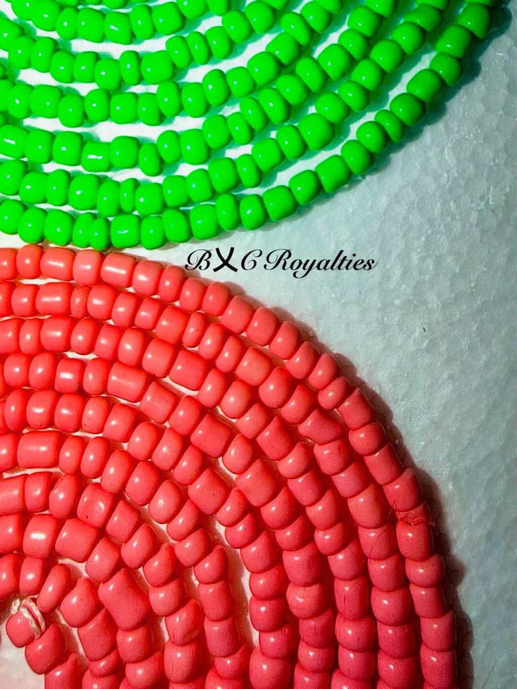 Two strands of beads, one green and one red, on a white background with 'BXC Royalties' branding.