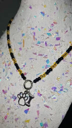 Necklace with paw and bone charm on a mannequin head with colorful background