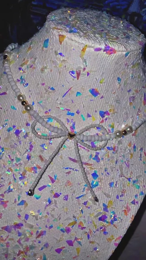 Mannequin head with colorful confetti pattern and decorative bow on a plain background