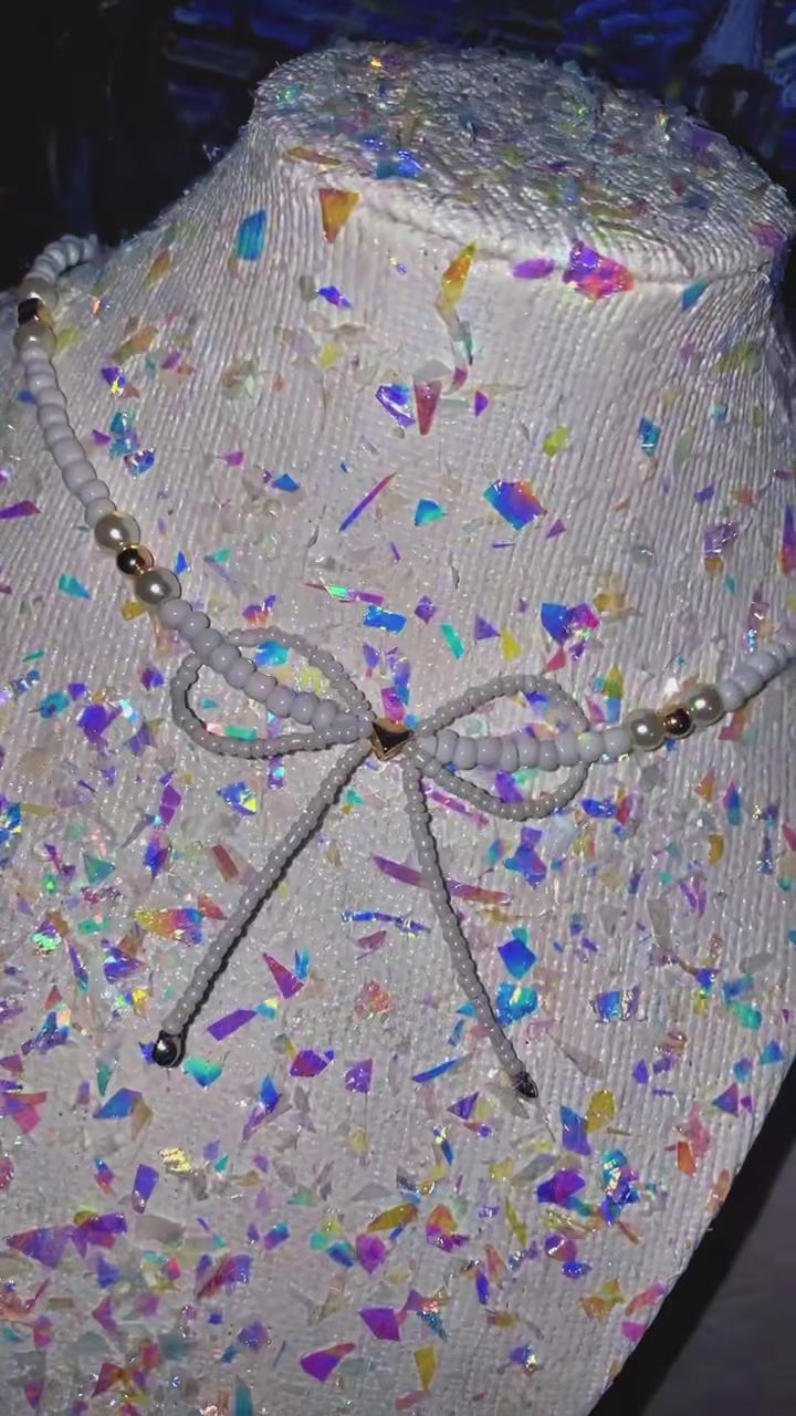 Mannequin head with colorful confetti pattern and decorative bow on a plain background